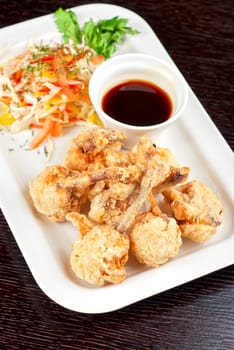 Fried chicken wings garnished with fresh vegetables with Teriyaki sauce