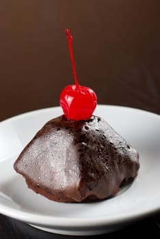 fresh baked chocolate cupcake with cherry on a wooden table