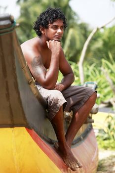 The young man sitting by a boat. Sri Lanka