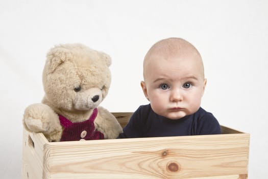 young child with toy bear (teddy bear) in wooden box.