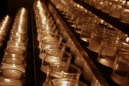 Rows of lit candles in a catholic church
