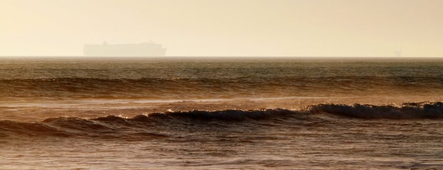Large container freighter on the horizon during sunset.