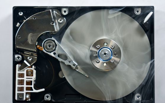 Defect hard disk drive with smoke. Open drive as symbol for data loss.