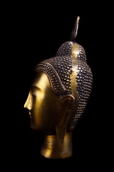 A side view of an antique sculpture of a buddha made of brass.