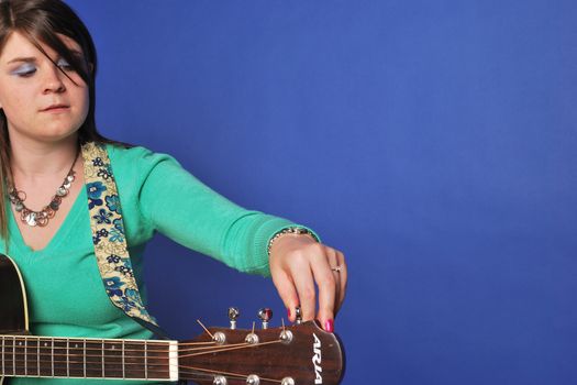 young woman tuning up her guitar