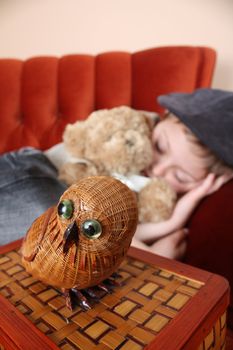 Young boy sleeping on a chair with his bear