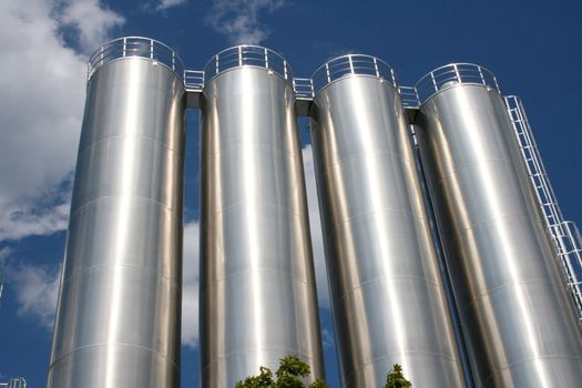 vier runde Industrietanks mit blauem Himmel als Hintergrund	
four round industrial tanks with blue sky as background