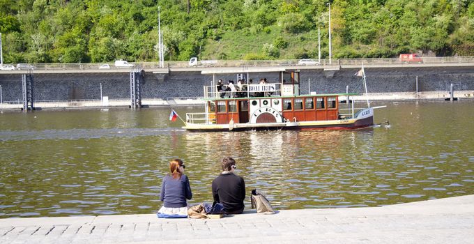 people sitting on the creek. rest. Prague, Czech Republic.