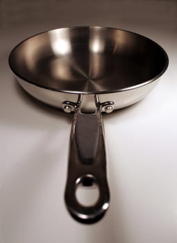 A stainless steel frying sitting with the handle facing out.
