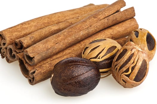 nutmeg and cinnamon sticks on a white background
