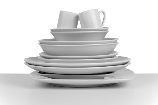 Pile of clean empty dishes and cups on white background.