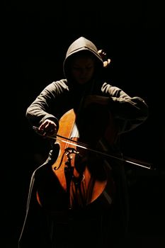 The girl with violoncello on a dark background