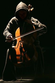 The girl with violoncello on a dark background