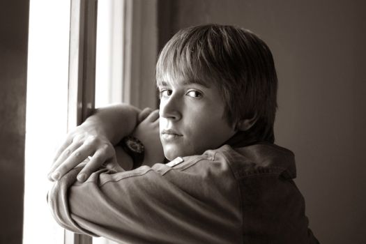 Portrait of the young man at a window. b/w+sepia