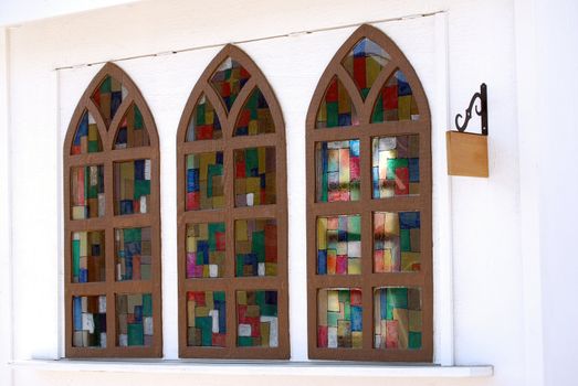 Horizontal image of three "fake" or "false" stained glass windows on a quaint little shop.