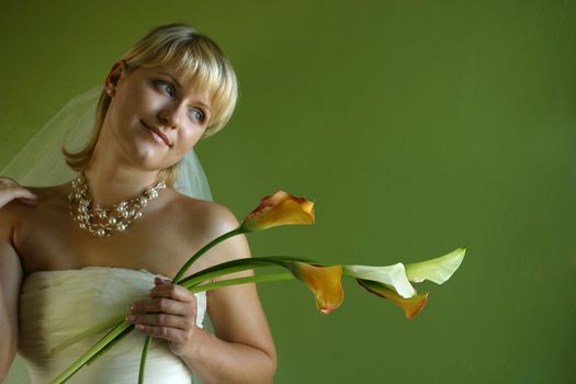 Five callas in hands of the beautiful bride on a green background