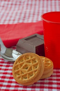 Close up of biscuits with chocolate, red cup and spoon in the background