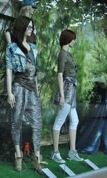 fashion boutique window with dressed mannequins with glass reflexion