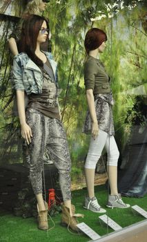 fashion boutique window with dressed mannequins with glass reflexion