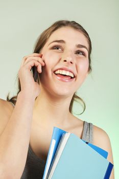 Smiling teenager girl holding blue plastic folders speaks on cellphone