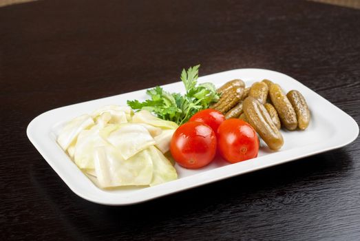 pickled vegetables of tomato, cucumber, cabbage at white plate