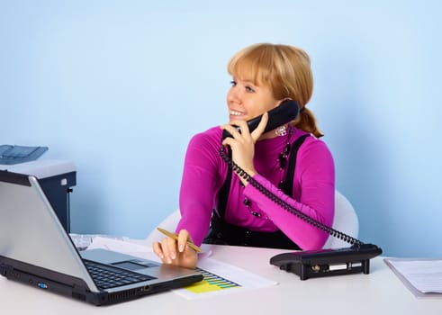 Attractive girl secretary talking on the phone in the office