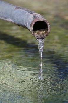 Water pouring out from pipe into clear water.