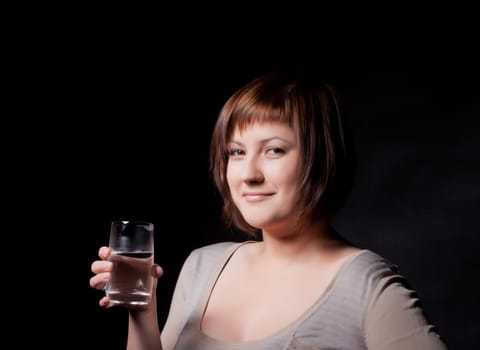 young woman with glass water, black background