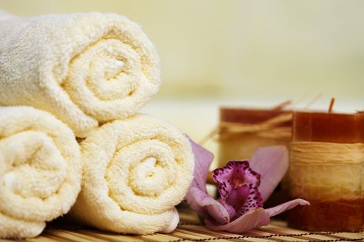 Still-life from towels, a flower and candles on a bamboo mat