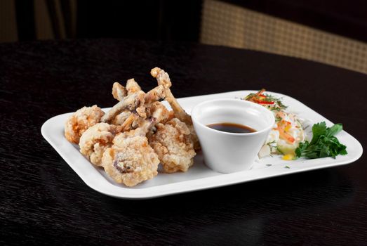 Fried chicken wings garnished with fresh vegetables with Teriyaki sauce