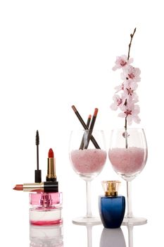 perfume bottles, lipsticks, cosmetics and cherry flower on white background
