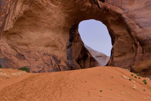 Centuries of wind erosion has made a cave in a rock in Monument Valley