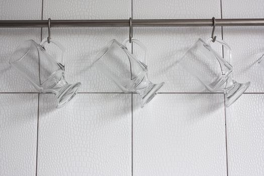 Glasses hanging on hooks against the white walls