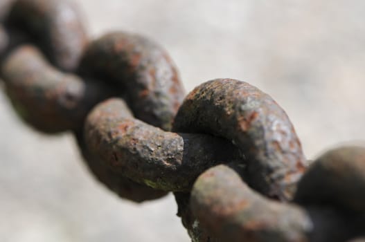 Extreme close-up of a rusted chain with big links on a blurred background