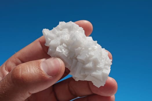 Salt crystals on the background of the sky in his hand.