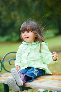 Clouse-up portrait pretty little girl sitting on a bench in the park