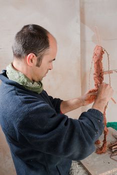 Artist in his studio working on a clay statue