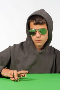 Cool teen posing with a tiny toy skateboard