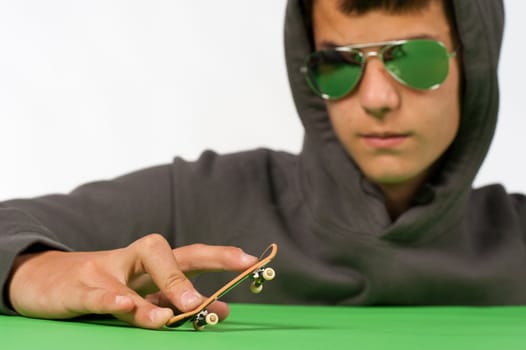 Cool teen posing with a tiny toy skateboard