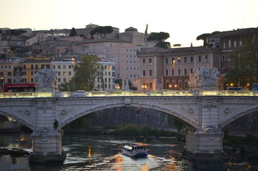 bridge in rome at dusk with a boat on the water