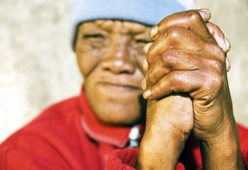 Old African woman with folded hands - focus on the weathered hands