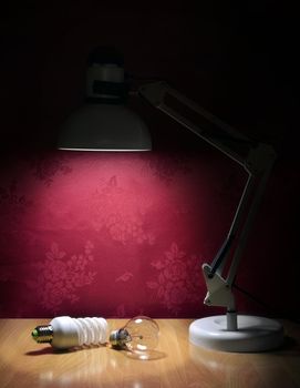 Ecologic light bulbs sitting on table and illuminated by lamp