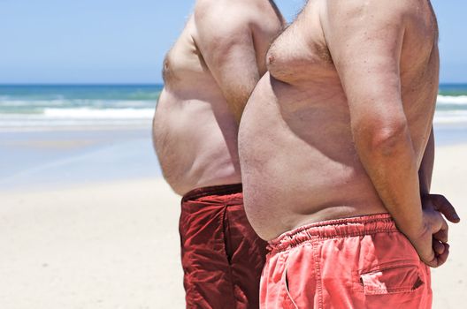 Close up of two obese fat men of the beach