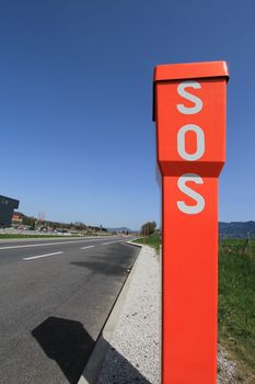 SOS orange sign next to a road by beautiful weather