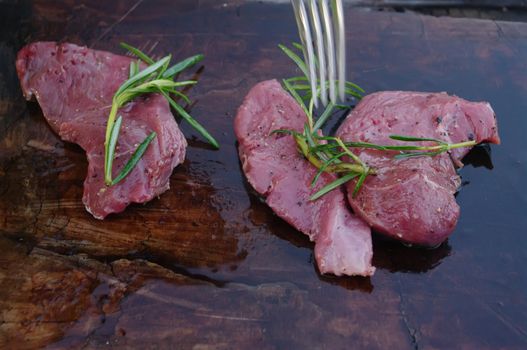 deer meat on bbq flagstone with rosemary