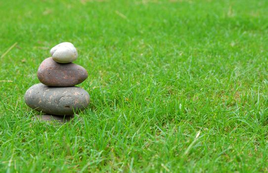A balance group of zen stones on green grass.