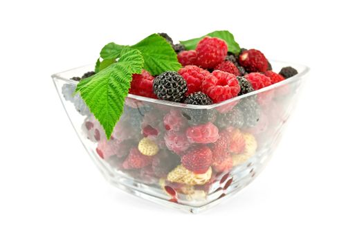 Red and white strawberries, raspberries, and blackberries in a glass isolated on white background
