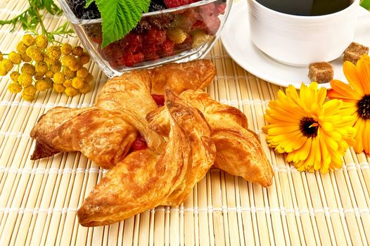 Bun with jam, berries in a glass cup, coffee cup in white porcelain, two of the flower marigold, tansy on a bamboo mat