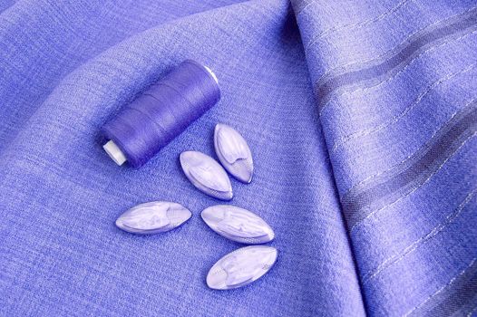 Threads and buttons on the lilac monotonous and striped fabric