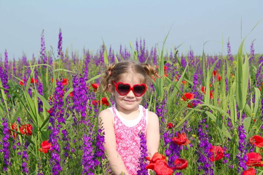 little girl standing in meadow with colorful flowers